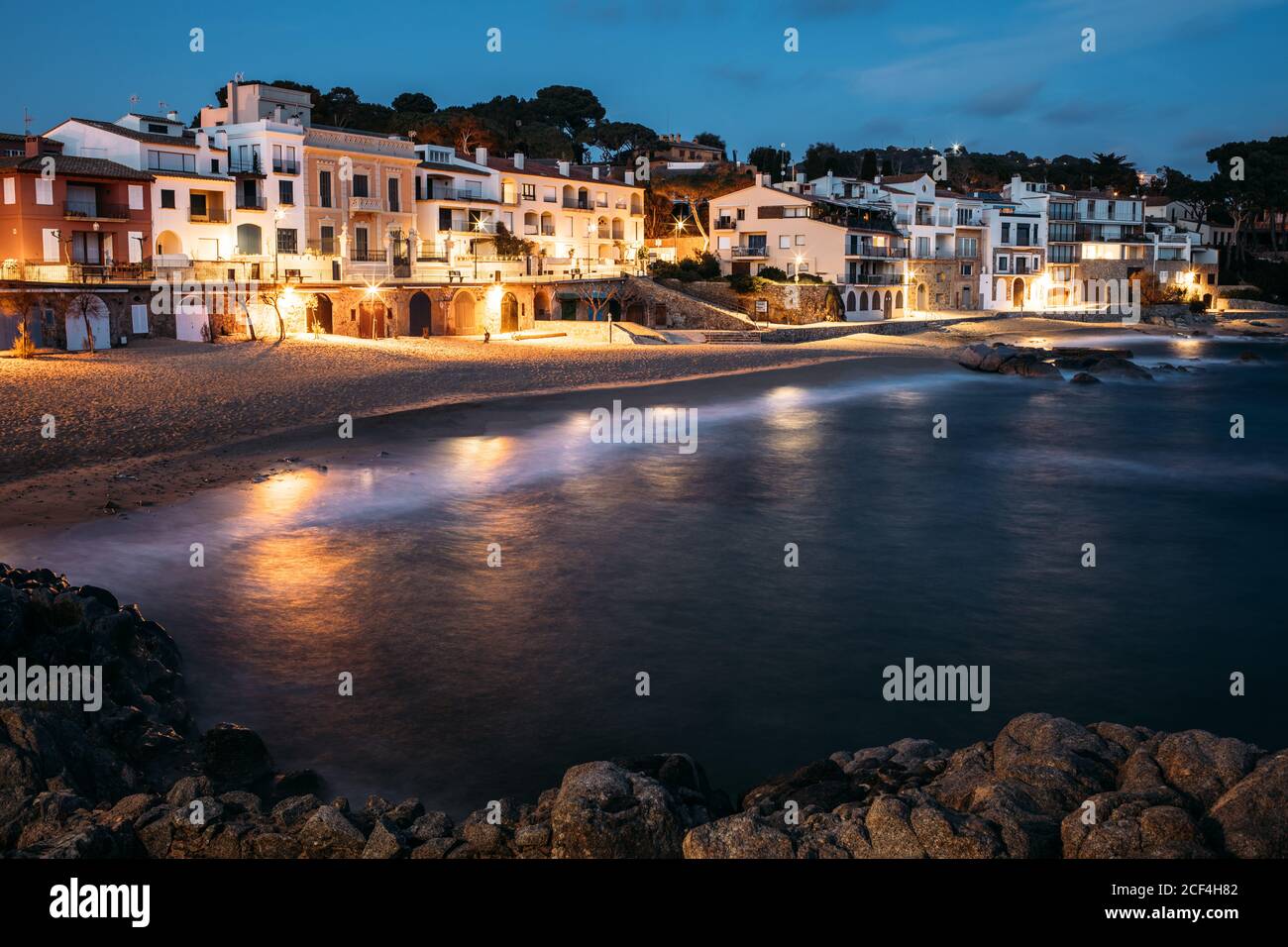 Cristallo blu scuro acqua che riflette luci sulla lanterna sulla riva con edifici architettonici in serata a Girona, Catalogna, Spagna Foto Stock