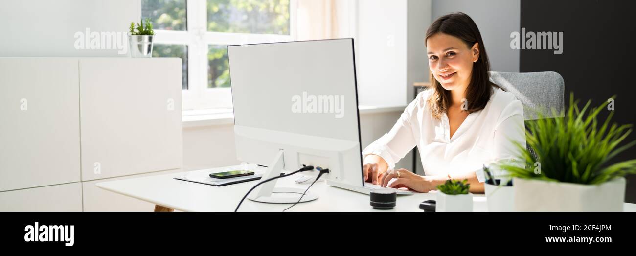 Donna di affari sicura alla scrivania di ufficio che funziona Foto Stock