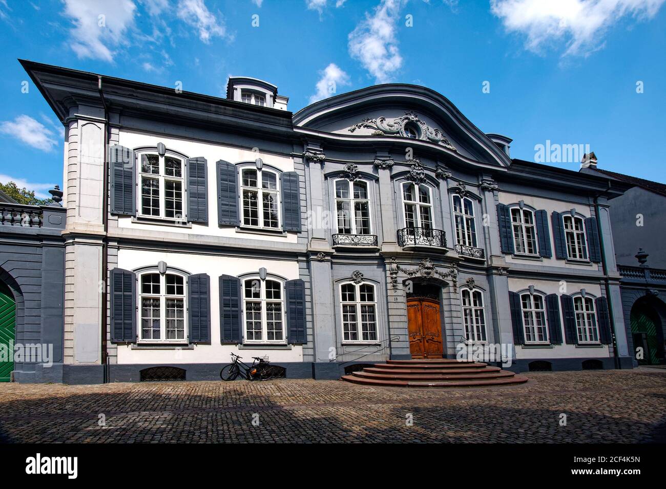 attraente vecchio edificio, facciata decorata, grandi finestre ad arco, balconi decorativi, persiane, grande porta matrimoniale in legno, scalini semicircolari, ciottoli Foto Stock