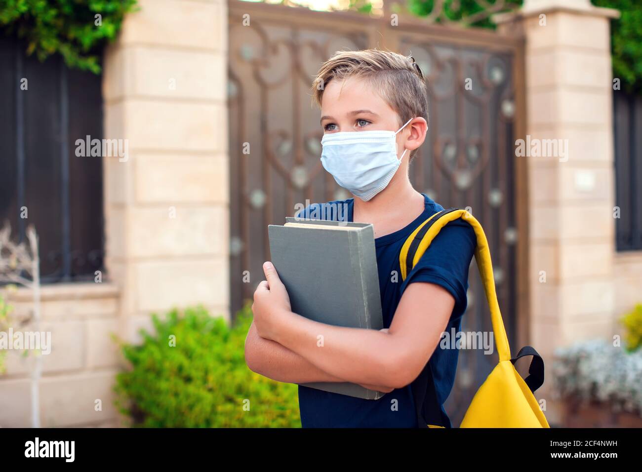 Pupillo con maschera facciale che rimane all'aperto. Torna a scuola in coronavirus pamdemid Foto Stock