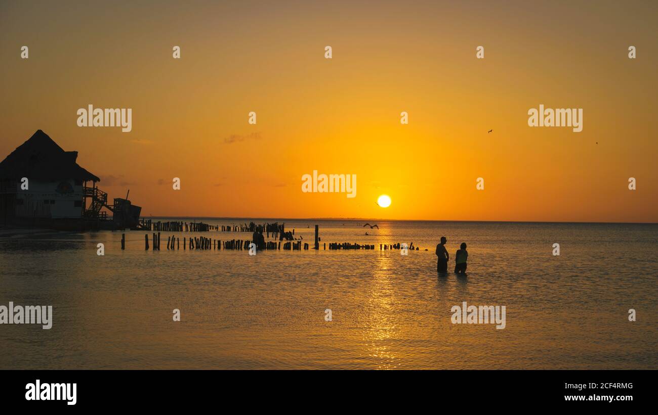 Paesaggio mozzafiato di casa solitaria molo nel vasto oceano sotto cielo luminoso e colorato al tramonto Foto Stock