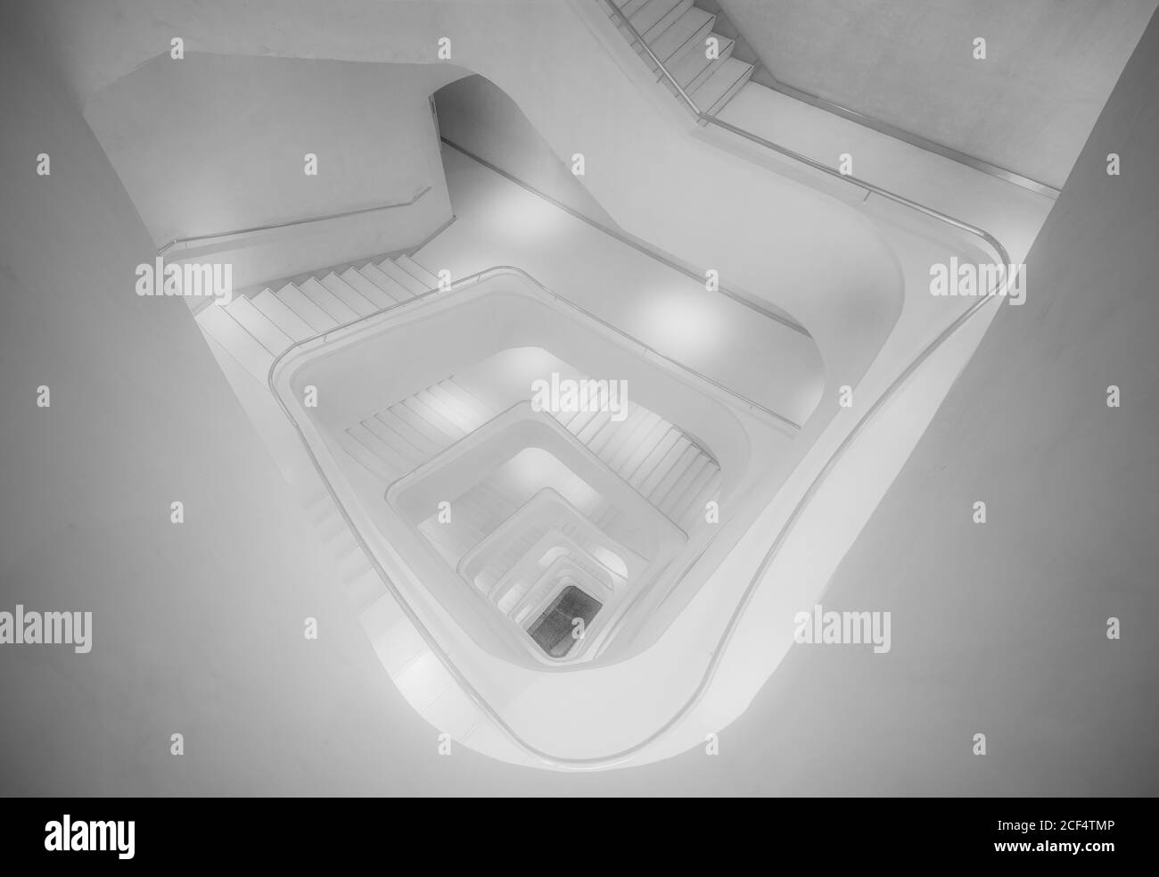 Dall'alto di una scala moderna illuminata di colore bianco andare a spirale Foto Stock
