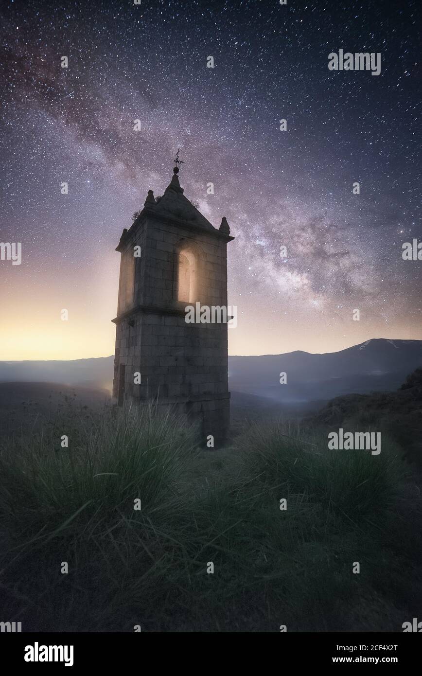 Antico edificio fortificato in una valle rocciosa sotto il luminoso cielo notturno con stelle maestose Foto Stock