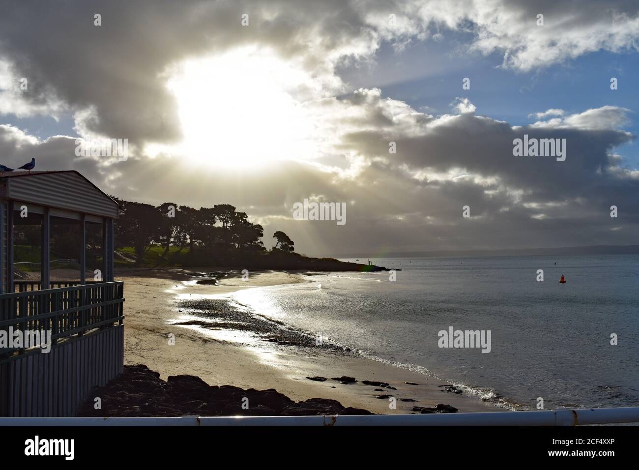 Cowes Beach vista dal Cowes Pier a Phillip Island, Australia. Il sole comincia a tramontare e si riflette nella sabbia bagnata e nel mare. Foto Stock