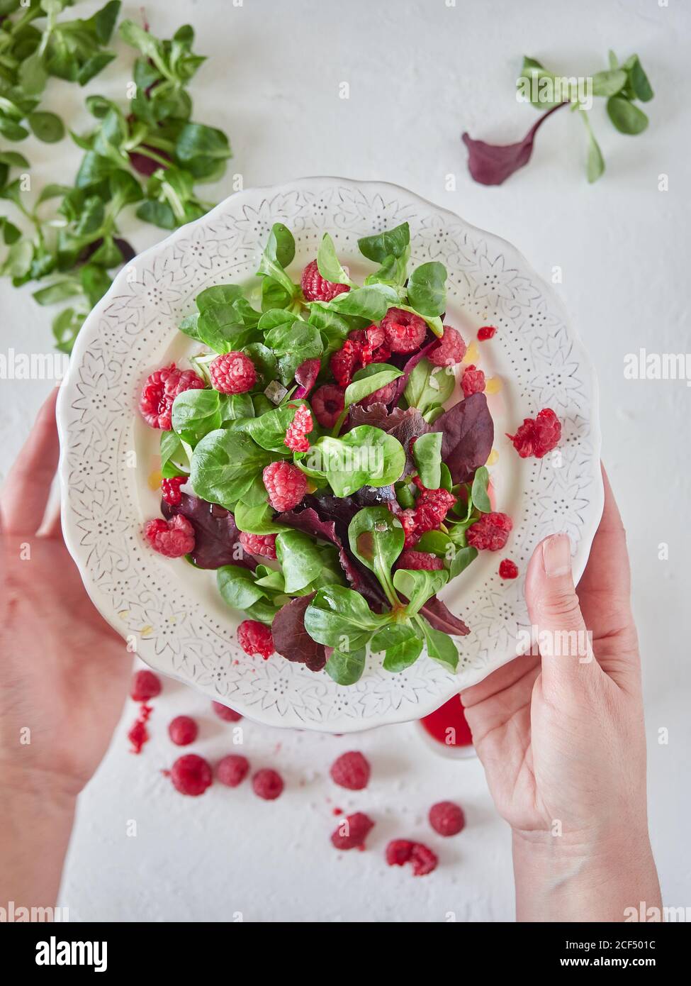 persona che tiene piatto con lampone e insalata di spinaci Foto Stock