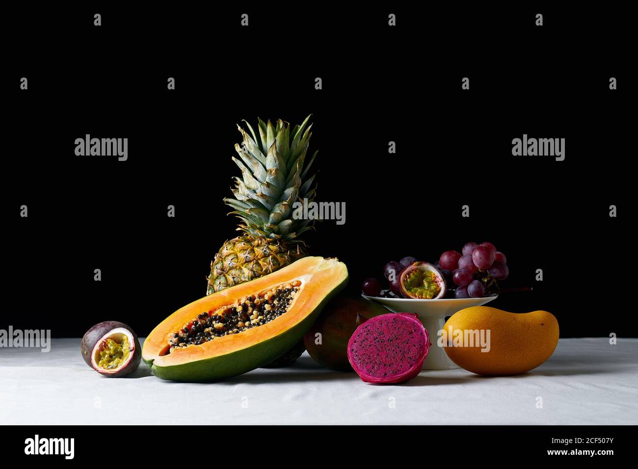 Ancora vita con frutta tropicale su tovaglia bianca e scura sfondo Foto Stock