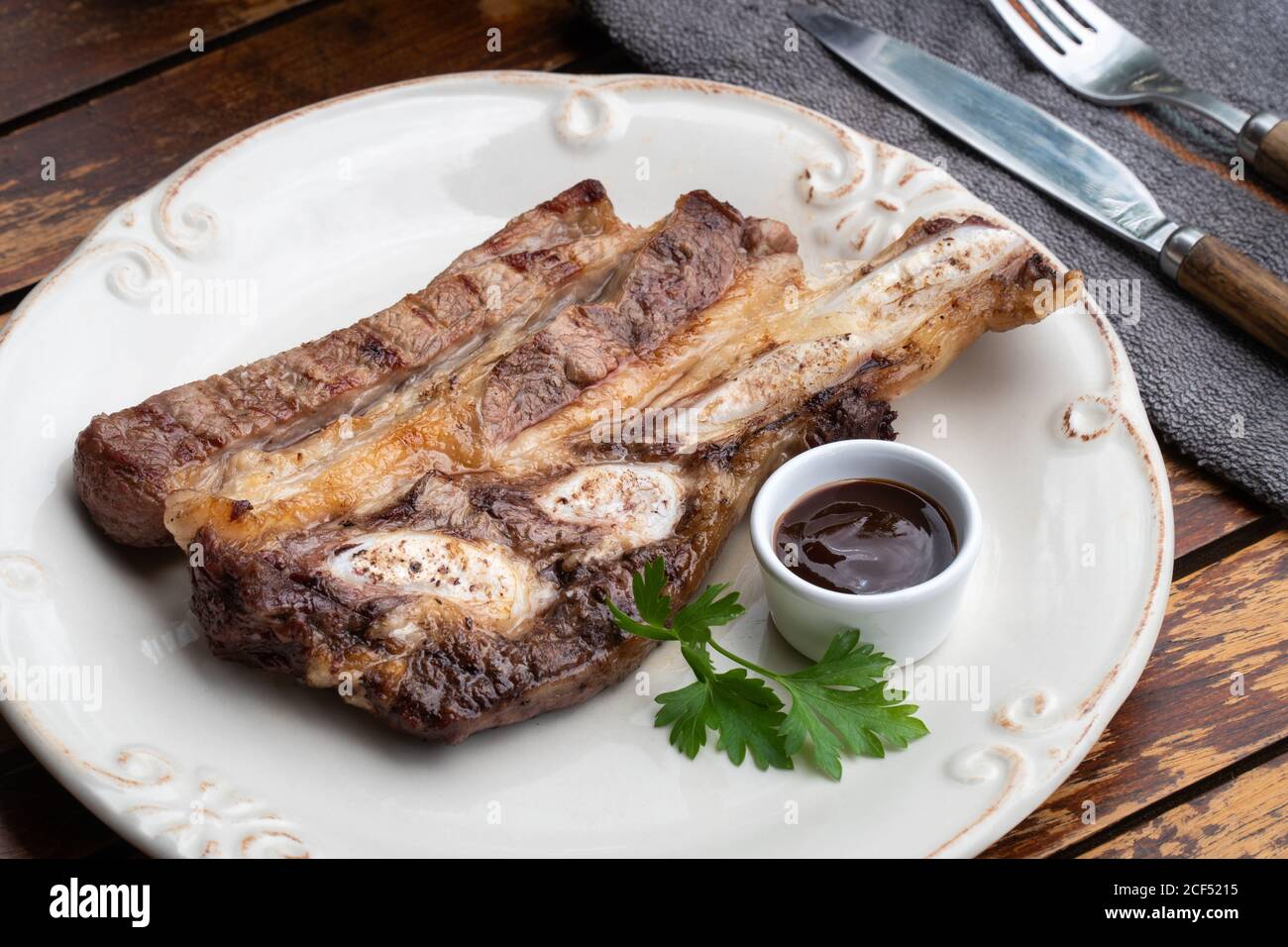 Gustoso piatto di carne alla griglia servito su piatto bianco con barbecue salsa Foto Stock