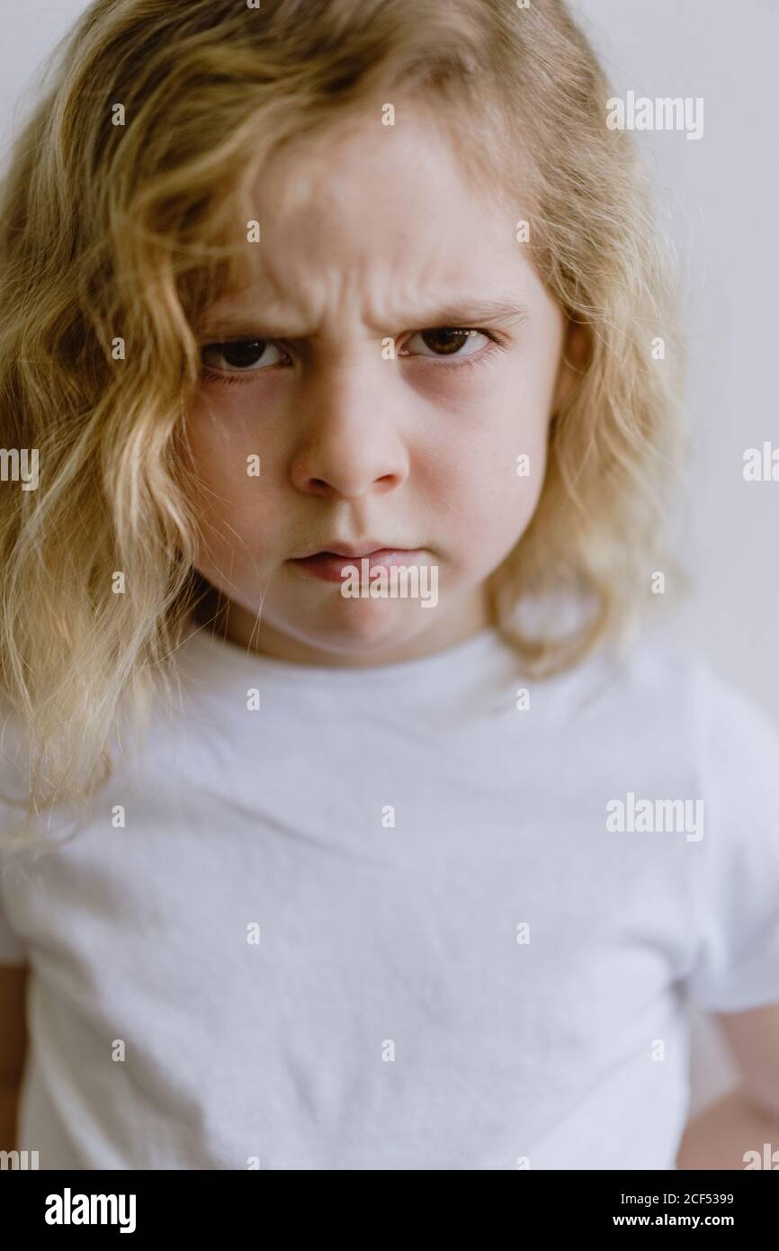 Deluso bambino piccolo in t-shirt casual guardando la macchina fotografica su sfondo bianco in studio Foto Stock