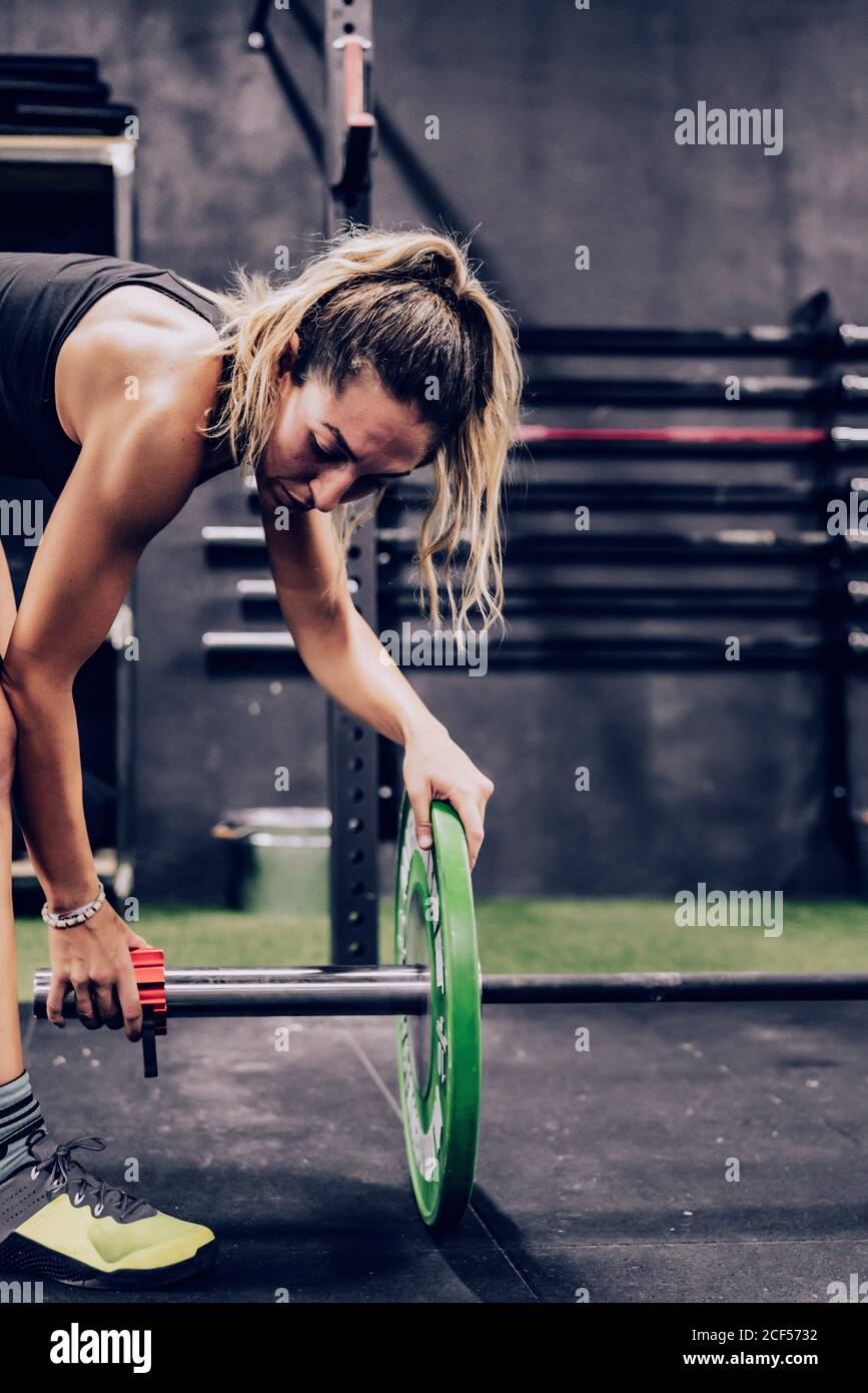 Vista laterale di seria Donna muscolare preparazione per l'allenamento con peso pesante in palestra Foto Stock