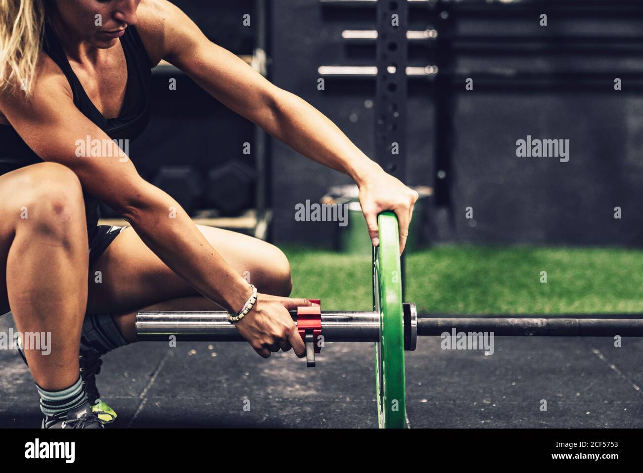 Vista laterale della Donna muscolare preparazione per l'allenamento con peso pesante in palestra Foto Stock