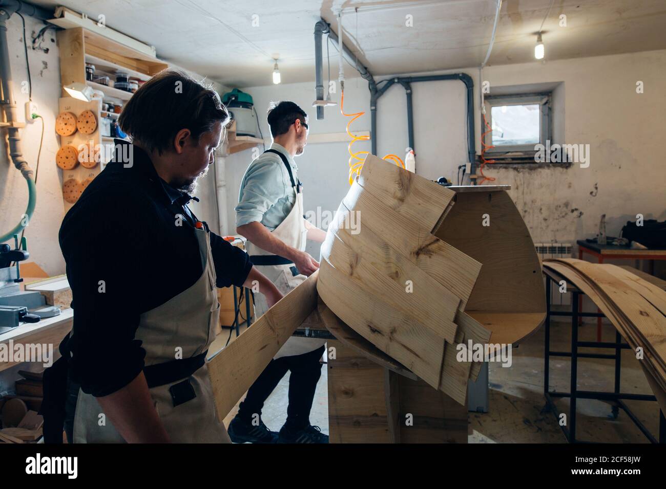 Mobile curvo incollato con morsetti. Pinze a vite per carpentiere per pressare spranghe di legno e colla bianca Foto Stock