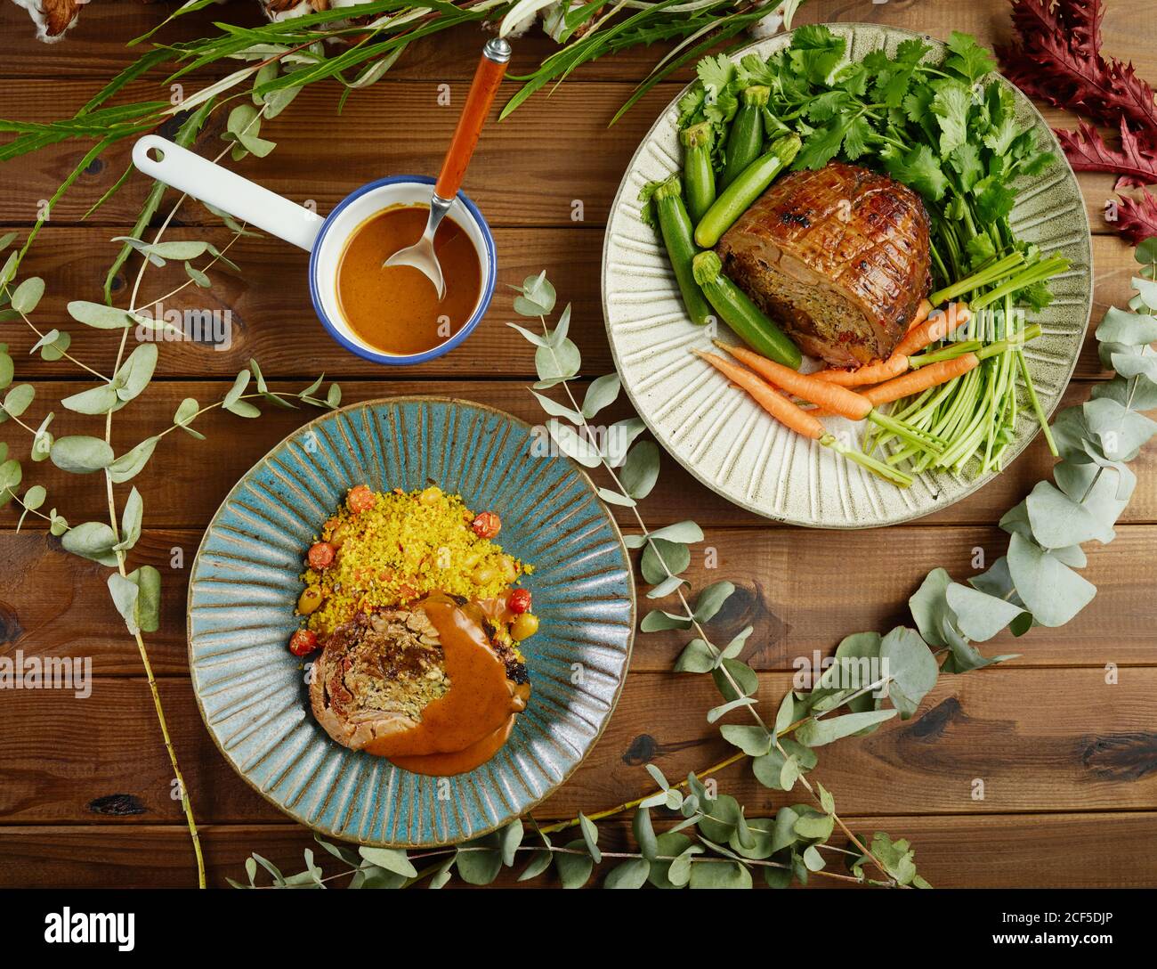 Gamba di lampada fritta imbottita e imbottita servita sui piatti con verdure fresche e riso tra ramoscelli verdi su legno tabella Foto Stock