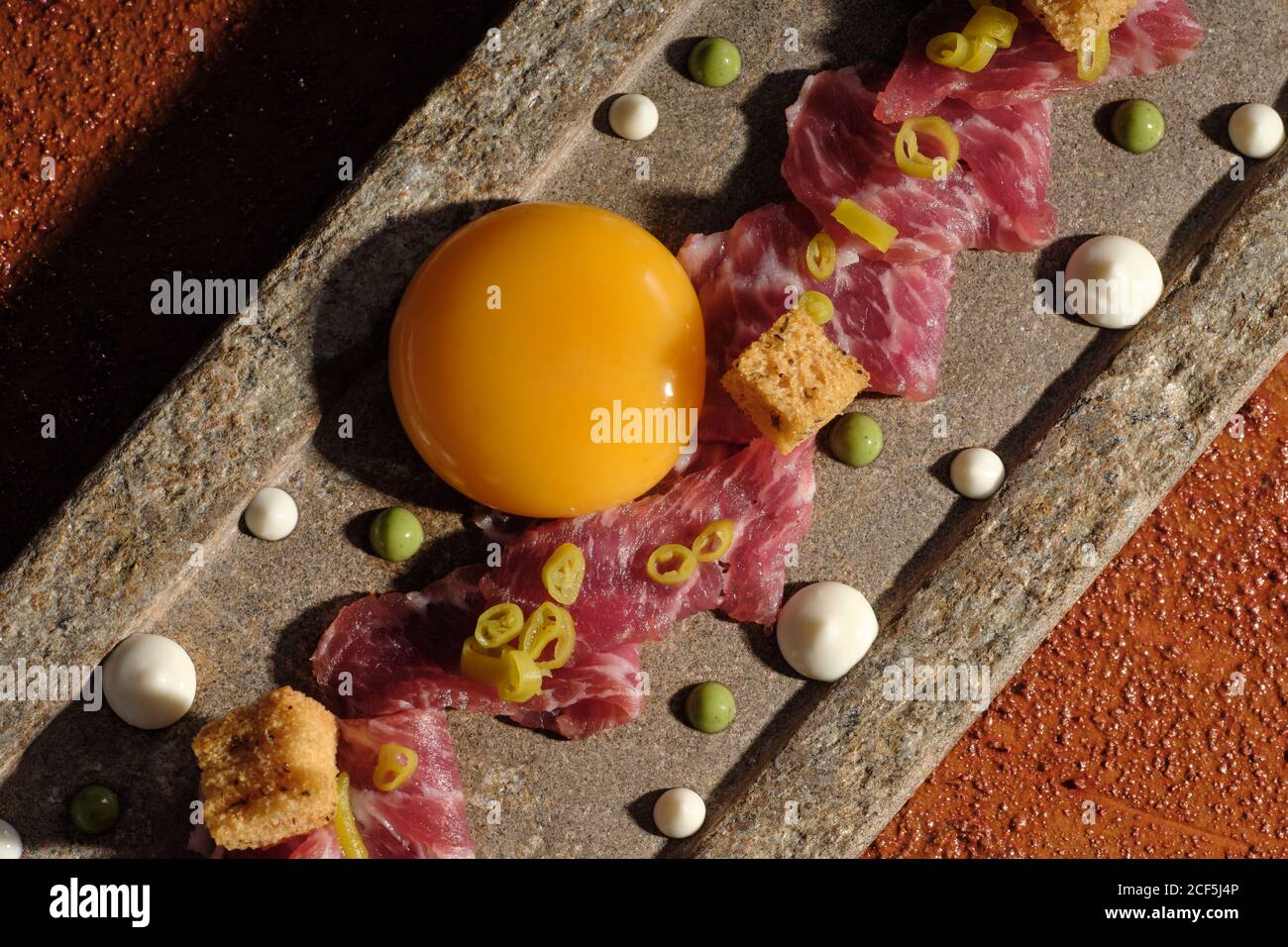 Vista dall'alto della scorza con carne e tuorlo d'uovo singolo sistemato su plunk in raggi solari Foto Stock