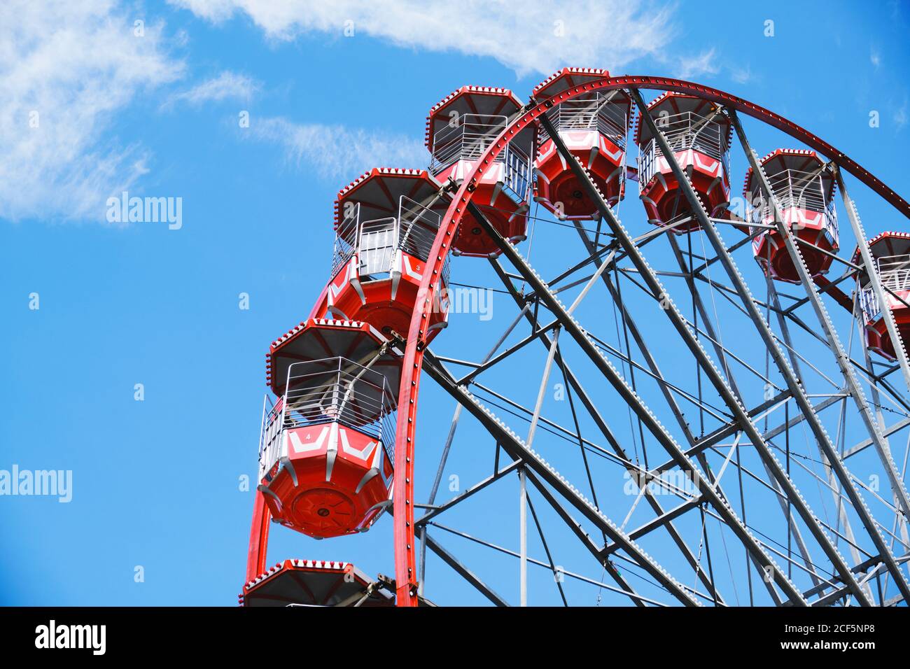 Dal basso della ruota panoramica con cabine rosse situate su parco divertimenti in giornata di sole con cielo blu Foto Stock