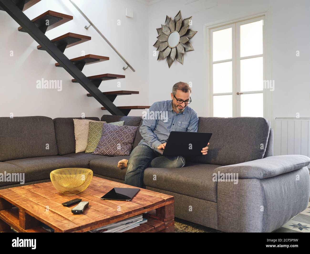 uomo che lavora da solo su un computer portatile sul divano nel soggiorno di casa Foto Stock