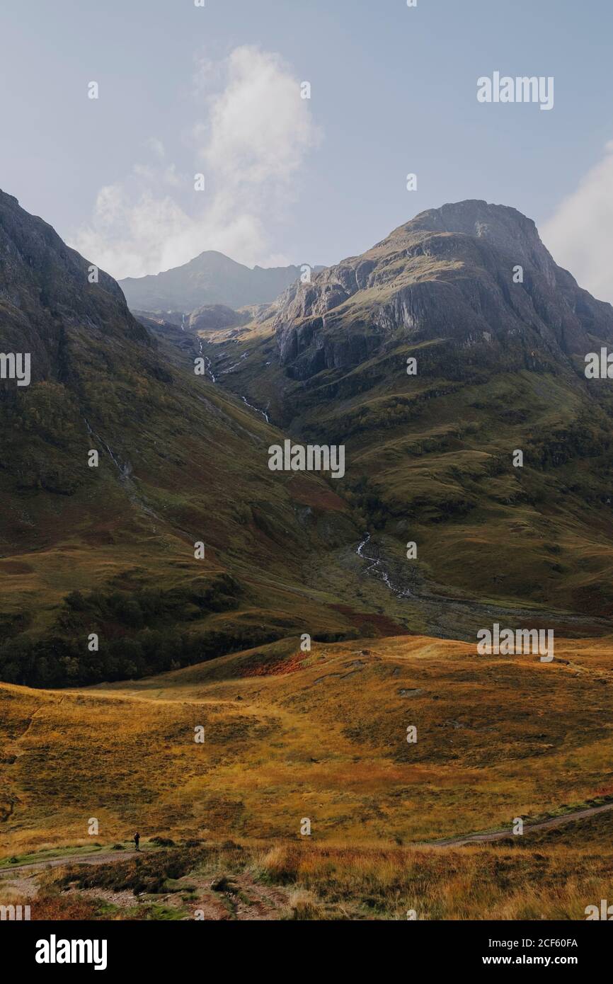 Tranquillo scenario della campagna scozzese con praterie gialle in roccia montagna contro cielo nuvoloso Foto Stock