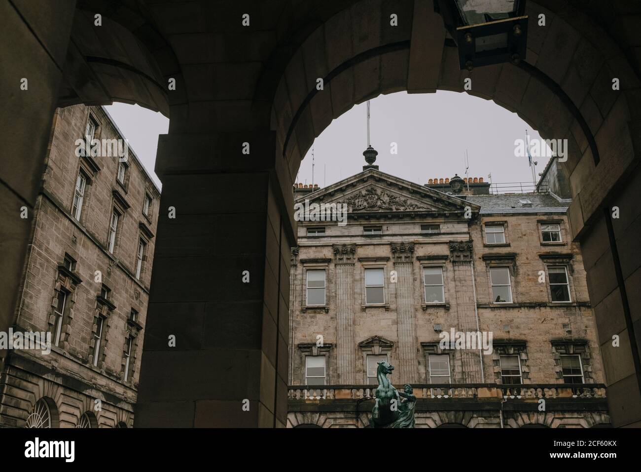 Basso angolo di vecchio edificio di Edinburgh City Chambers con statua in cortile visto da sotto l'arco Foto Stock