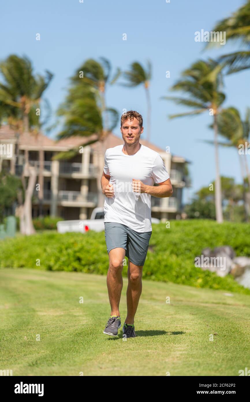 Un giovane corridore sano che si sta allenando a fare jogging felice sull'erba all'aperto. Stile di vita attivo e in forma. Foto Stock