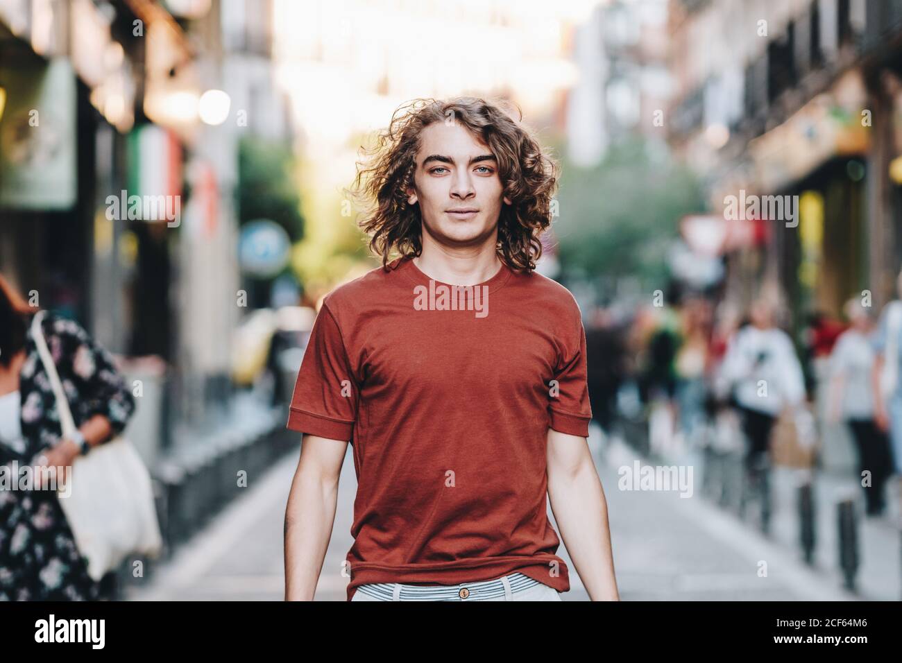 Bell'uomo in t-shirt passeggiando lungo la strada urbana estiva Foto Stock