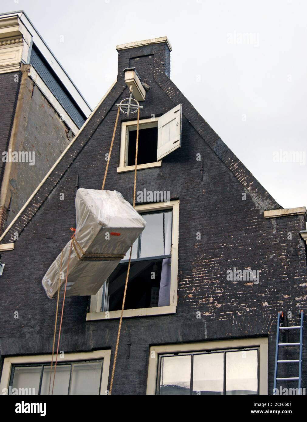 I mobili vengono sollevati al piano superiore di una casa a timpano ad Amsterdam, Olanda, utilizzando un sistema di pulegge e funi per esterni. Foto Stock