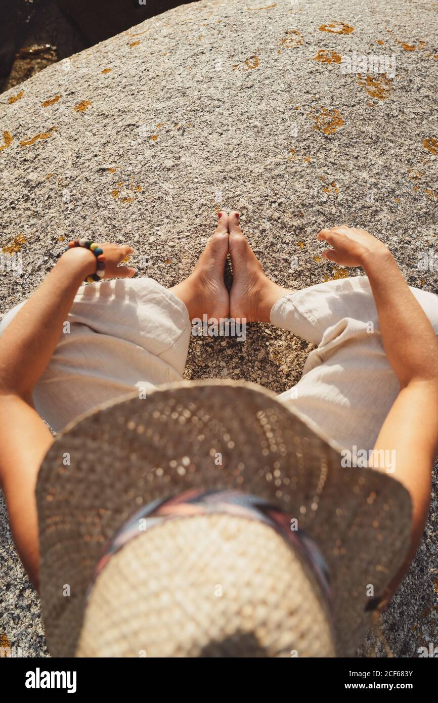 Vista dall'alto della persona che si trova su una pietra ruvida calda e meditando alla luce del sole calmo Foto Stock