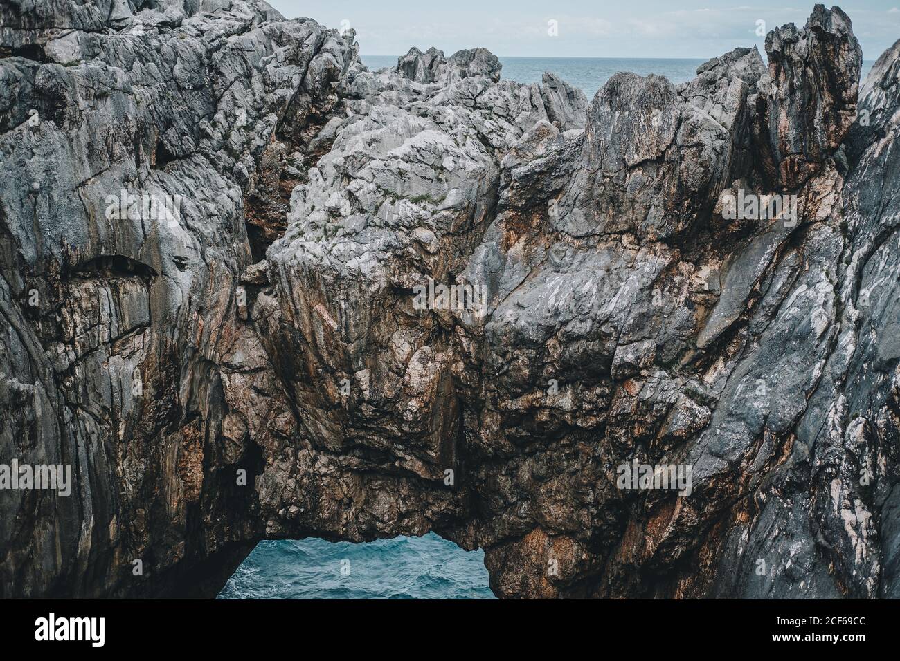 Vista mozzafiato delle scogliere rocciose con arco naturale e bella laguna in giorno nuvoloso Foto Stock