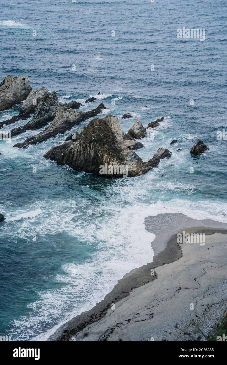 Cime rocciose circondate da acqua schiumosa in giornata ventosa Foto Stock