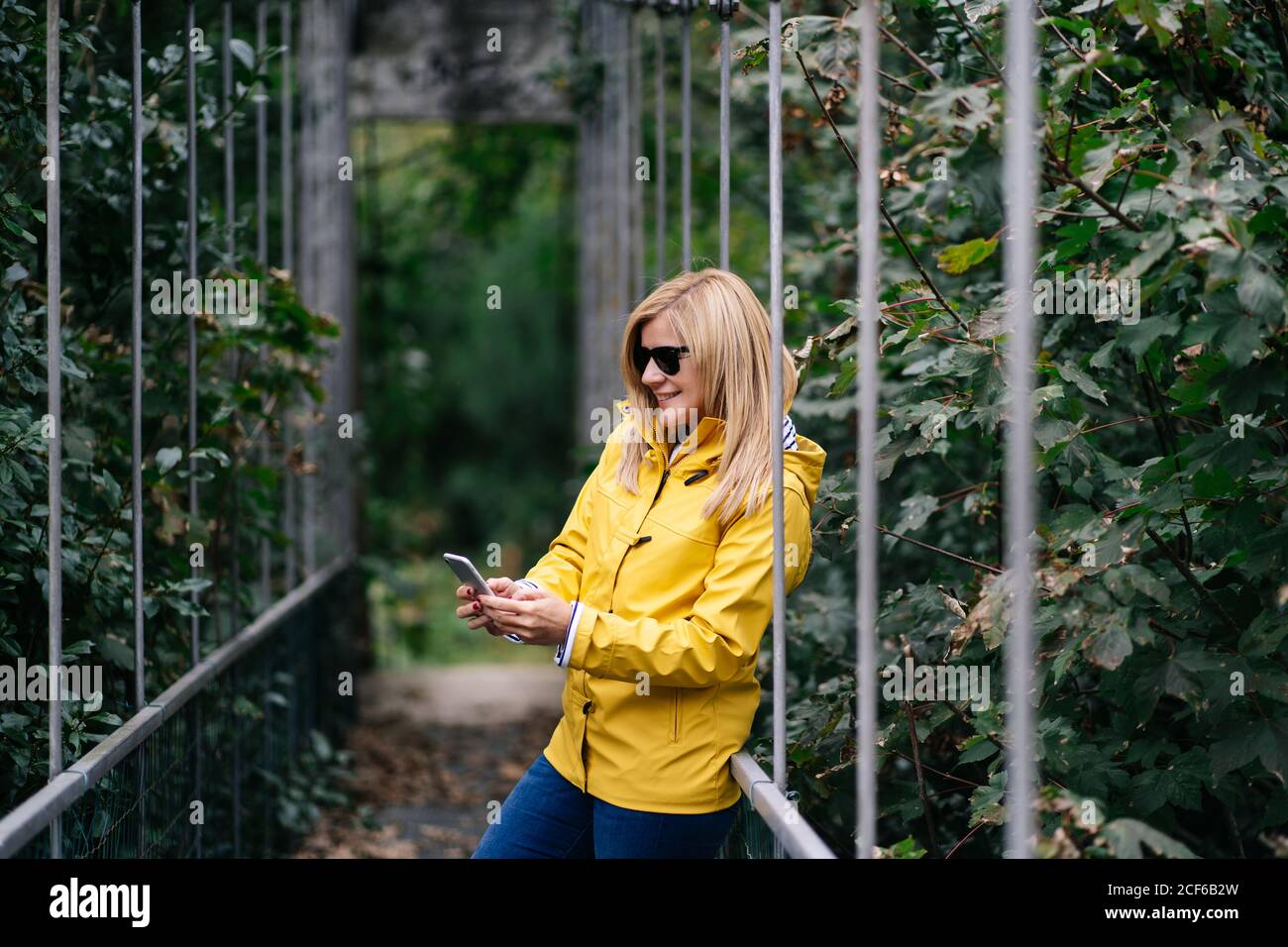 Felice viaggiatore femmina che prende selfie sul ponte sospeso in estate Foto Stock