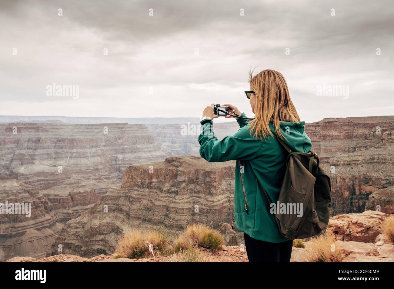 Vista laterale della donna in giacca con zaino che fotografa la vista pittorica del canyon negli Stati Uniti Foto Stock