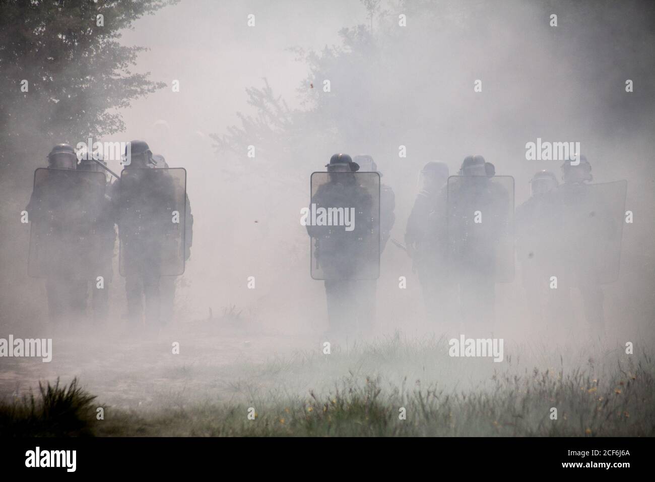 22 maggio 2018, Notre Dame Des Landes, Bretagne, Francia: Prima linea di polizia anti-sommossa che appare da una nuvola di gas lacrimogeni dopo aver spinto gli attivisti ZAD indietro durante la Resistance.seconda ondata di scontri, durante una serie di sfratti che durarono una settimana nel territorio occupato francese la ZAD (zona di difesa). Dopo 50 anni di lotta contro il progetto di costruzione dell'aeroporto di Nantes e oltre 10 anni di squatting su 4000 ettari di terreno, 300 attivisti che vivono nella zona sono stati attaccati militari dal governo che ha voluto porre fine al progetto autonomo. Mille anti Foto Stock