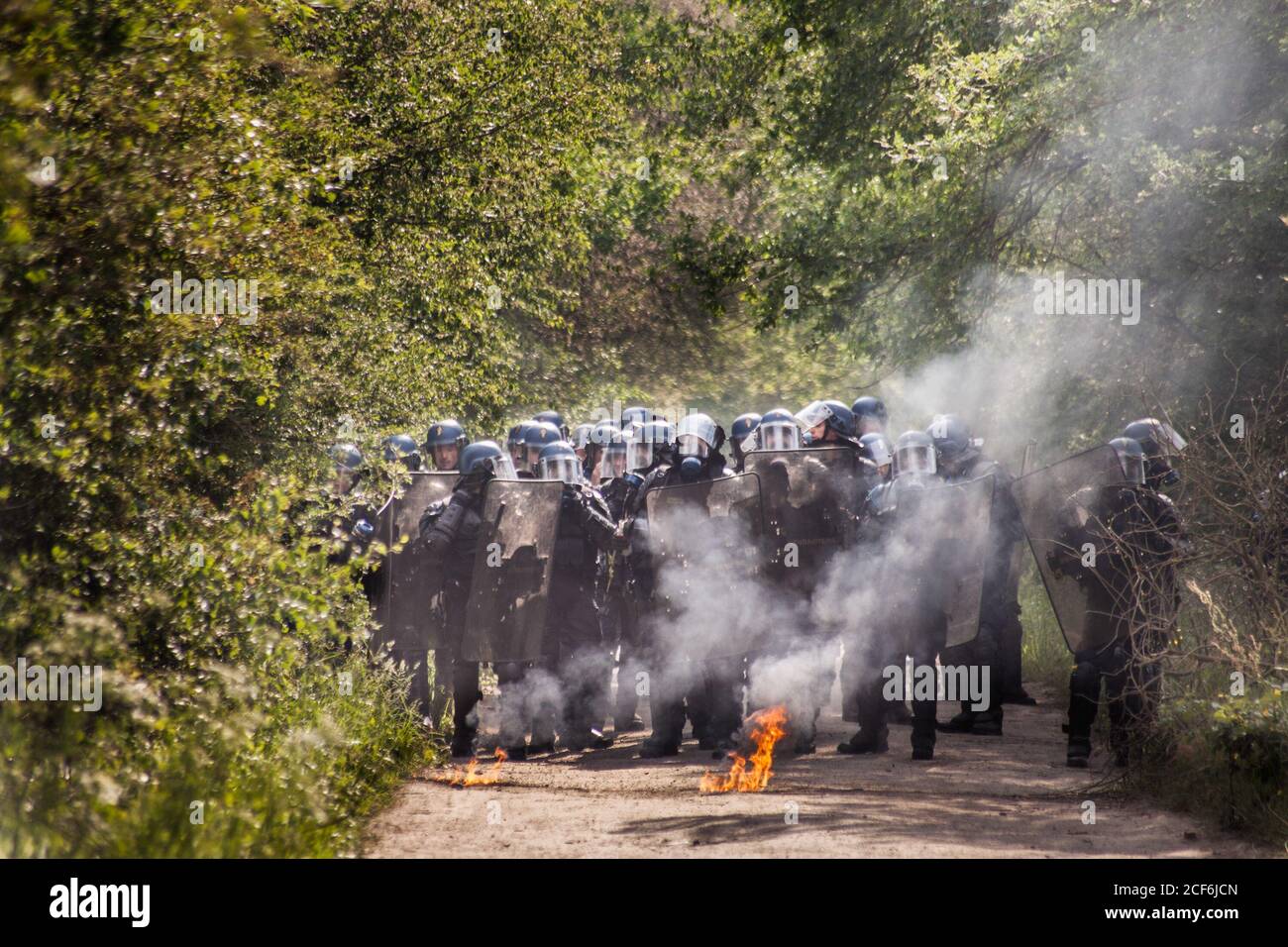 La polizia anti-sommossa si prepara ad attaccare gli attivisti dopo aver ricevuto pochi cocktail molotov dal gruppo di resistenza dello ZAD.seconda ondata di scontri, durante una serie di sfratti che durarono una settimana nel territorio occupato francese la ZAD (zona da difendere). Dopo 50 anni di lotta contro il progetto di costruzione dell'aeroporto di Nantes e oltre 10 anni di squatting su 4000 ettari di terreno, 300 attivisti che vivono nella zona sono stati attaccati militari dal governo che ha voluto porre fine al progetto autonomo. Un migliaio di poliziotti antisommossa distrusse il 80% delle case auto-costruite. Foto Stock