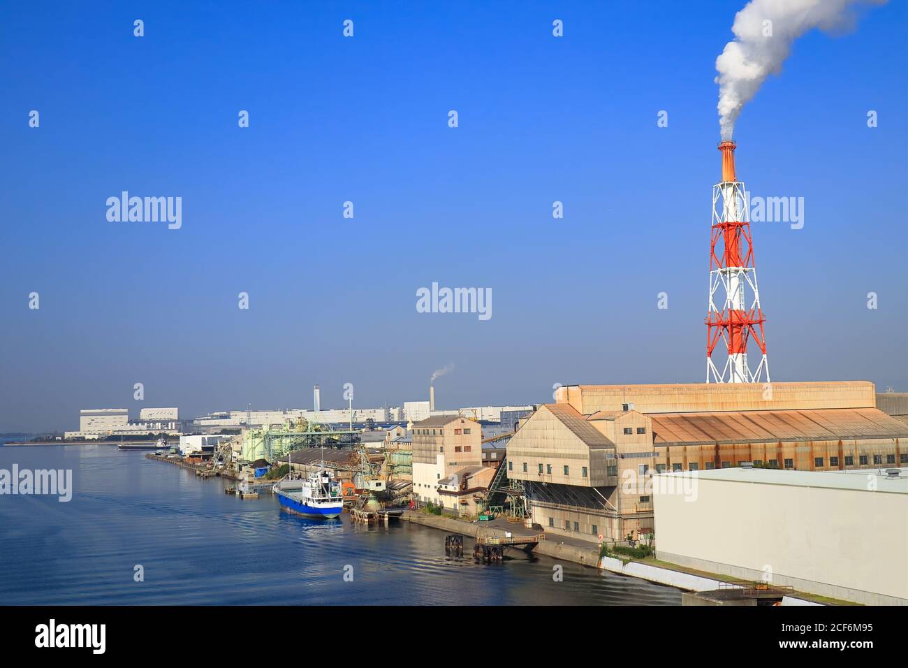 La nave costiera giapponese Cargo Hold è ormeggiata al porto industriale circondato da edifici di fabbrica nella Baia di Osaka, Giappone. Foto Stock