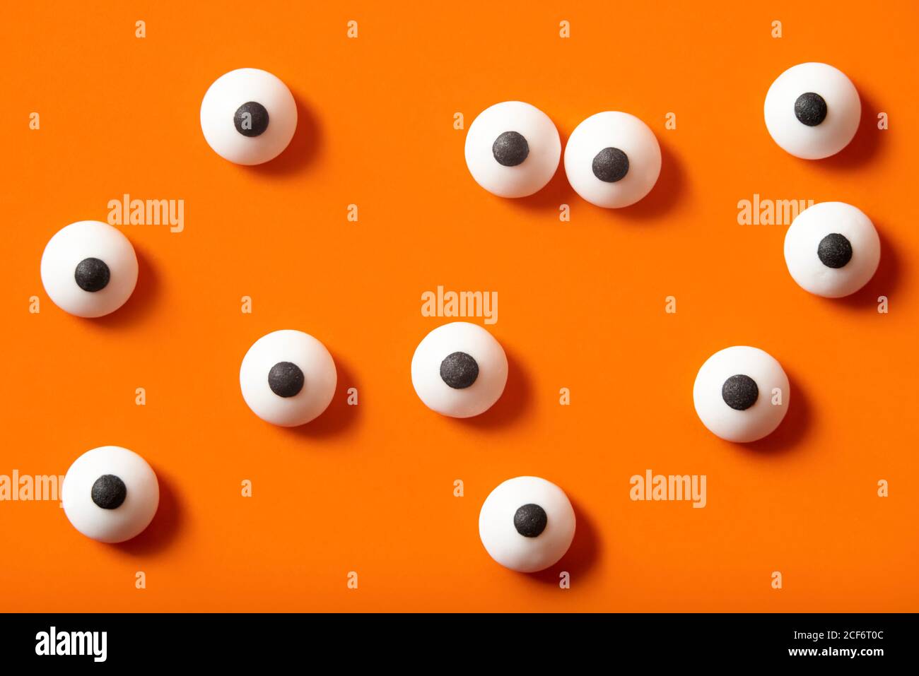 Sfondo di Halloween, molti occhi bianchi puntati su sfondo arancione Foto Stock