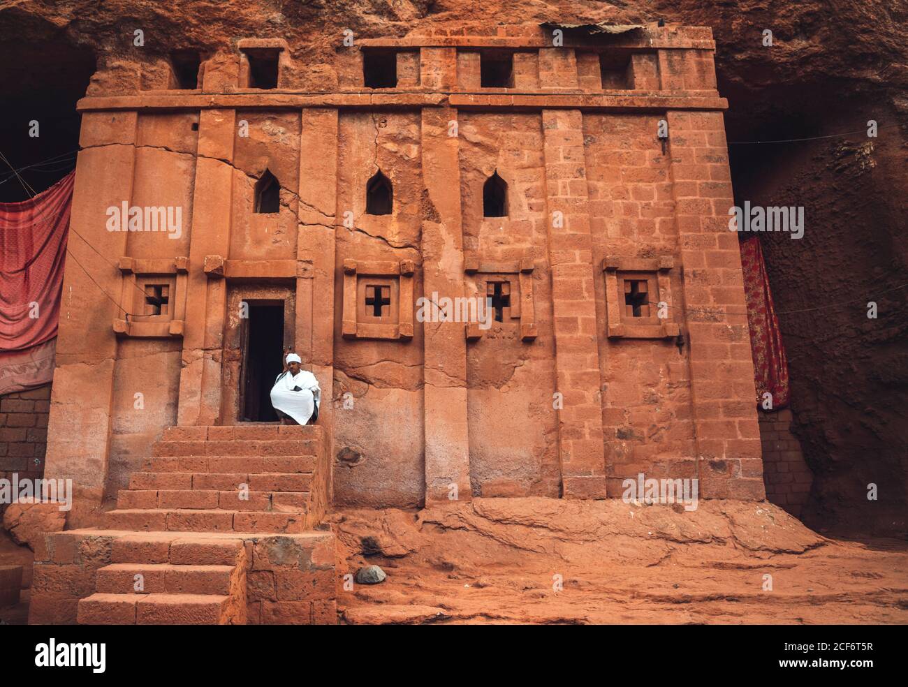 Lalibela, Etiopia - 04 novembre 2018: Sacerdote seduto sul portico della vecchia chiesa ortodossa scavata nella roccia a Lalibela, Etiopia Foto Stock