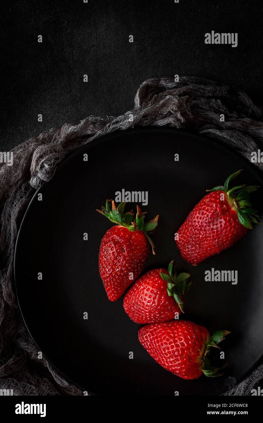 Fragole rosse e fresche piatte in piatto nero Foto Stock