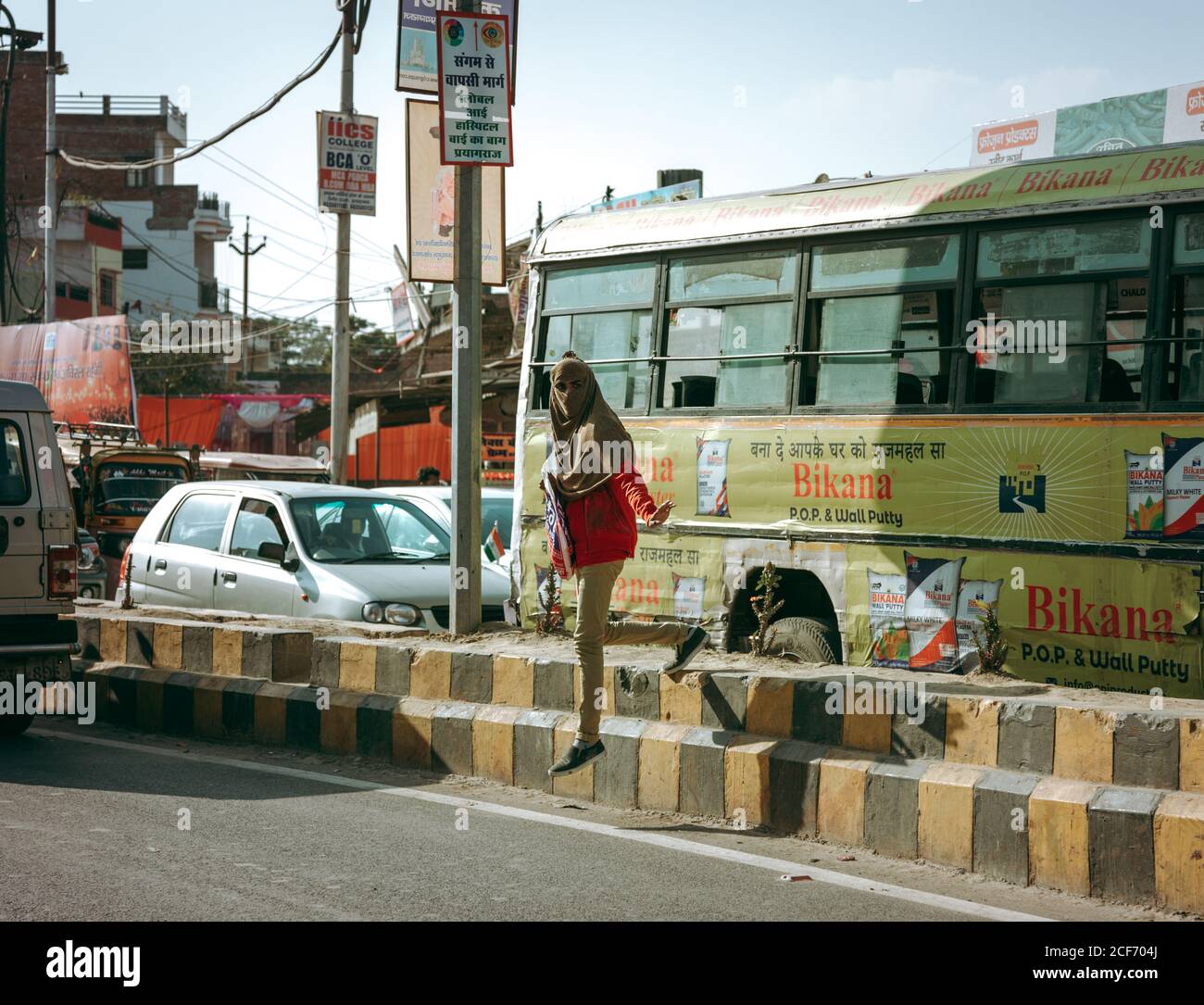 Allahabad, India - Febbraio, 2018: Giovane donna con testa coperta che attraversa la strada tra auto e autobus Foto Stock