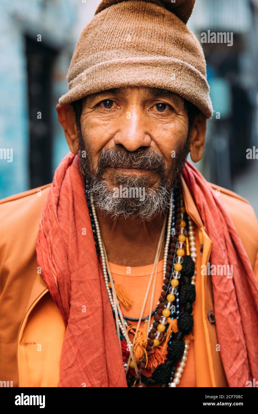 Varanasi, India - FEBBRAIO, 2018: Primo piano ritratto di un anziano indiano che indossa abiti tradizionali arancioni contro sfondo sfocato Foto Stock