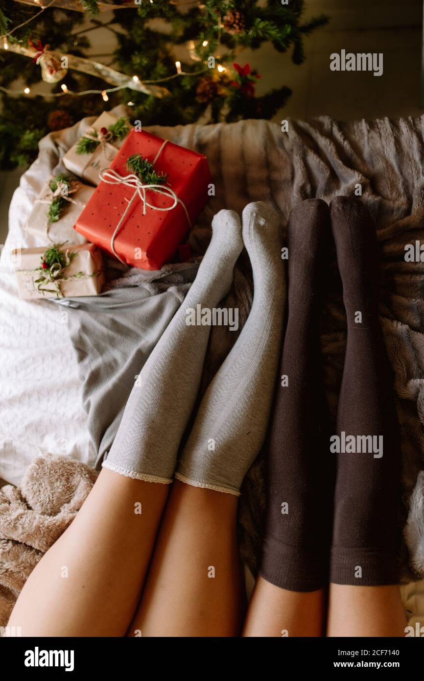 Due amici con gambaletti in inverno in vacanza a casa vicino albero di natale in interni accoglienti con regali di natale. Foto Stock