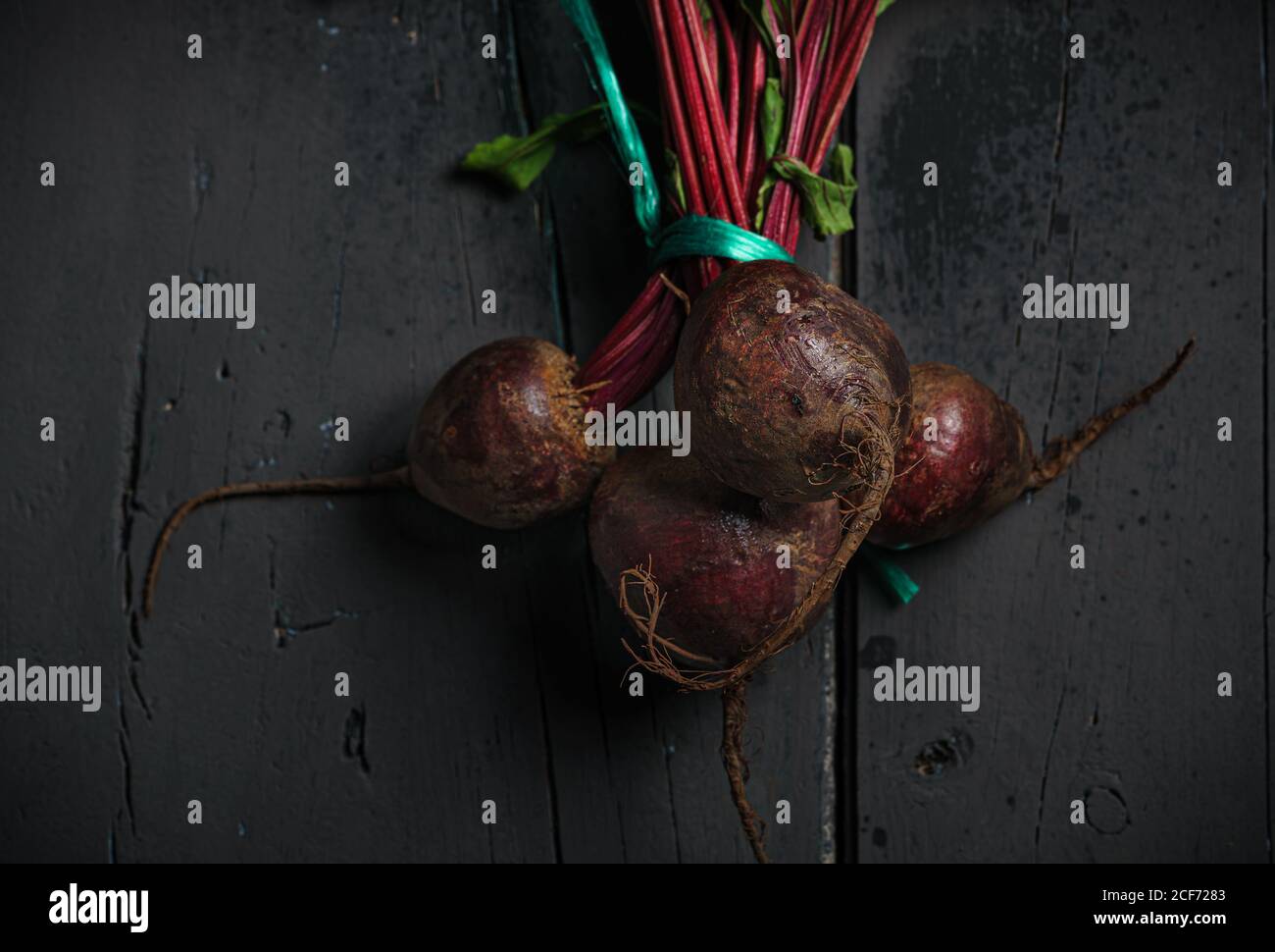 Da sopra barbabietole di zucchero rosso scuro su gambo con verde foglie su sfondo nero Foto Stock