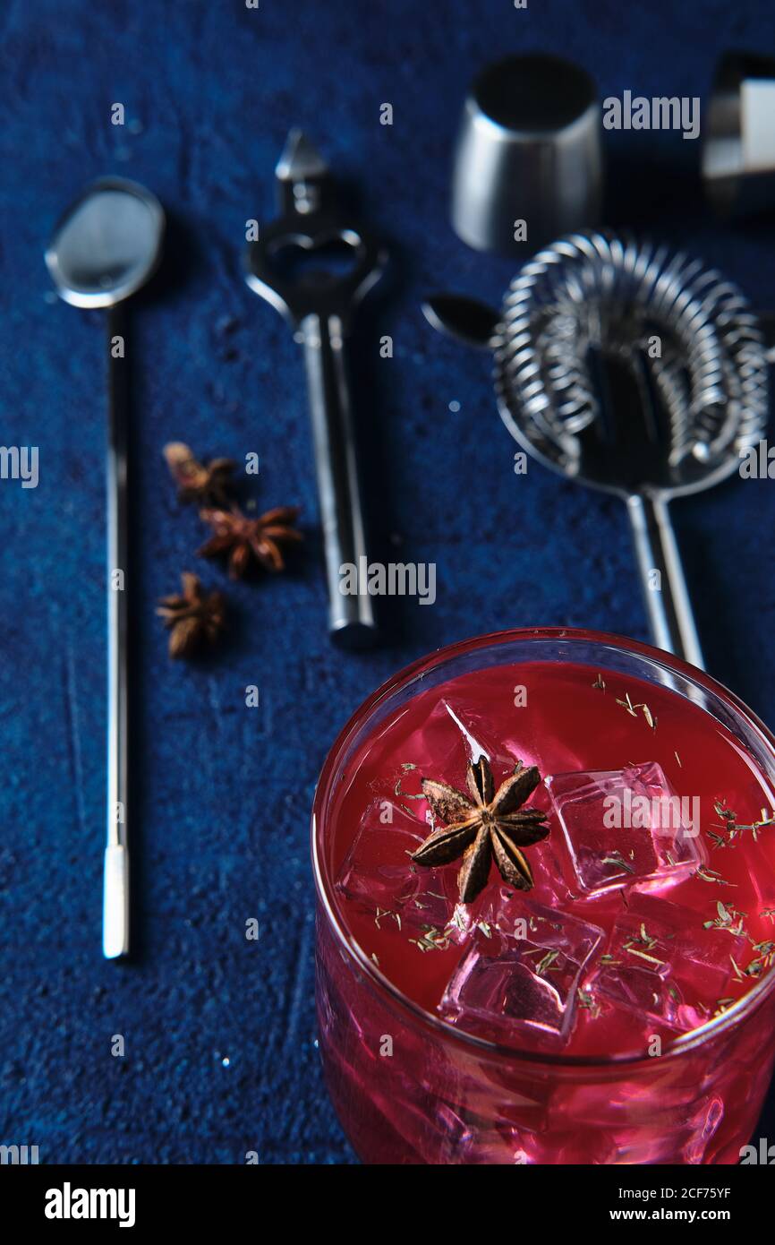 Deliziosi cocktail rossi e utensili da barman sul tavolo Foto Stock