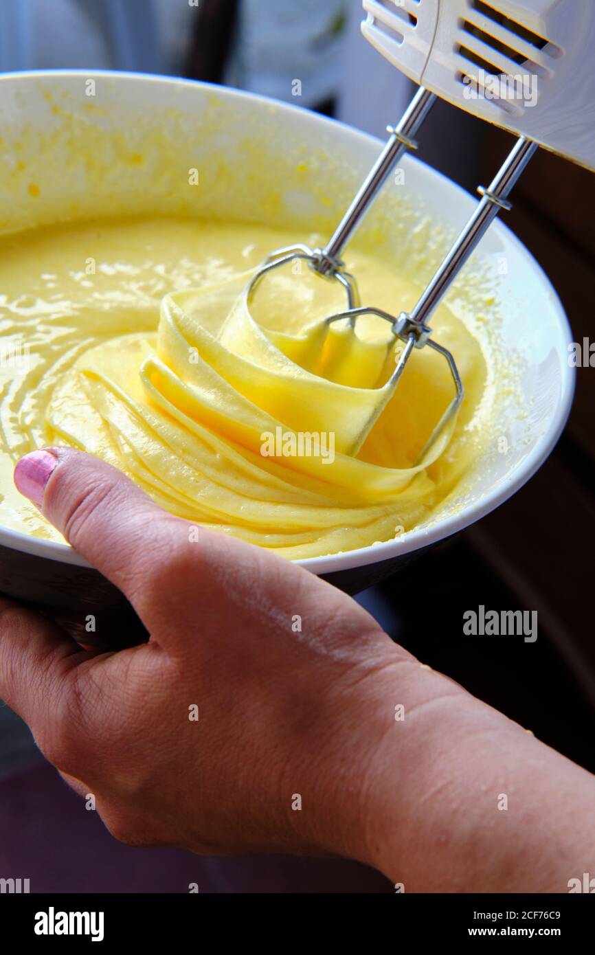 Da sopra anonima Donna uso mixer per preparare pastella per pasticceria in cucina a casa Foto Stock