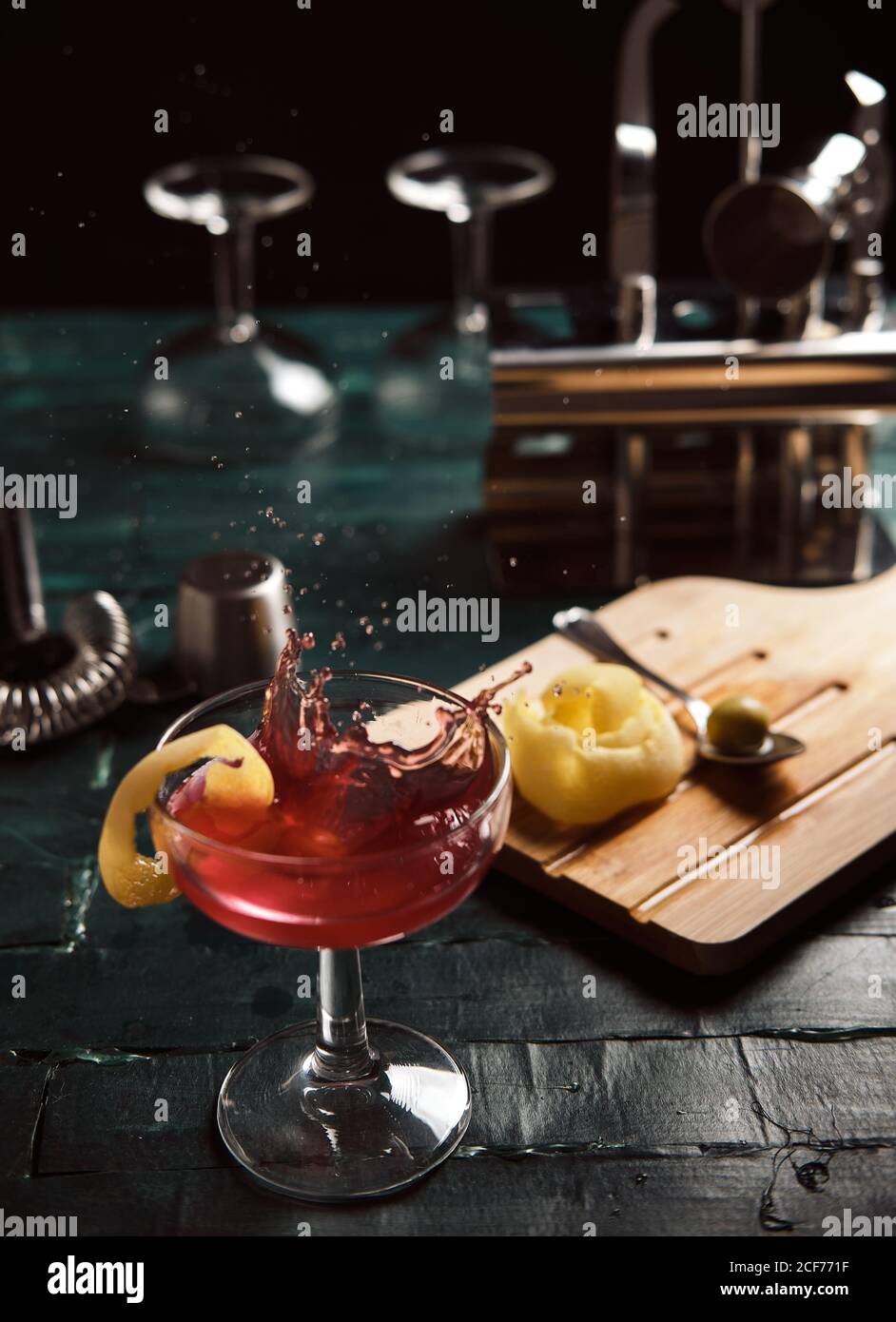 Dall'alto del cocktail alcolico rosso con spruzzi serviti in coupé vetro guarnito con limone sul bancone bar Foto Stock