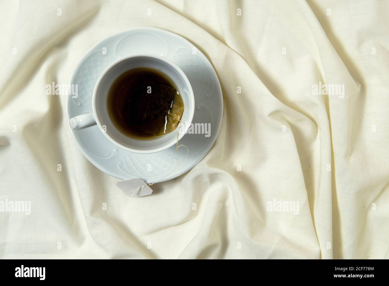 Vista dall'alto della tazza bianca con tè a letto per una deliziosa colazione a letto Foto Stock