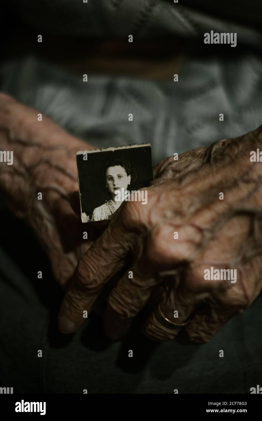 Da sopra anonima anziana persona che tiene la foto anziana a casa Foto Stock