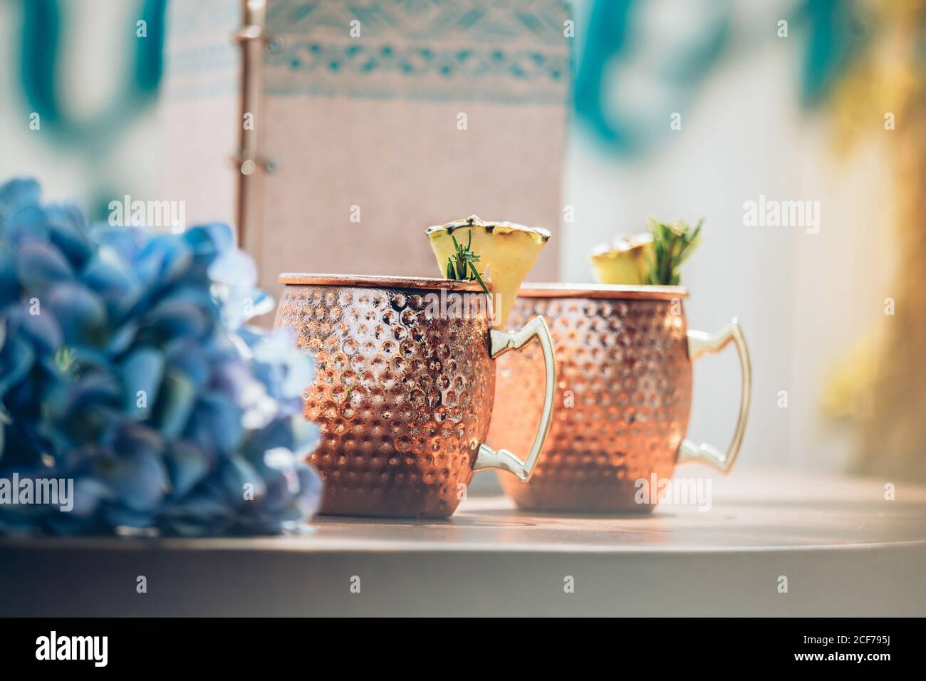 Cocktail Mule Mosca freddo con birra allo zenzero e vodka con calce servita in tazze di rame tradizionale al bancone bar con fiori Foto Stock