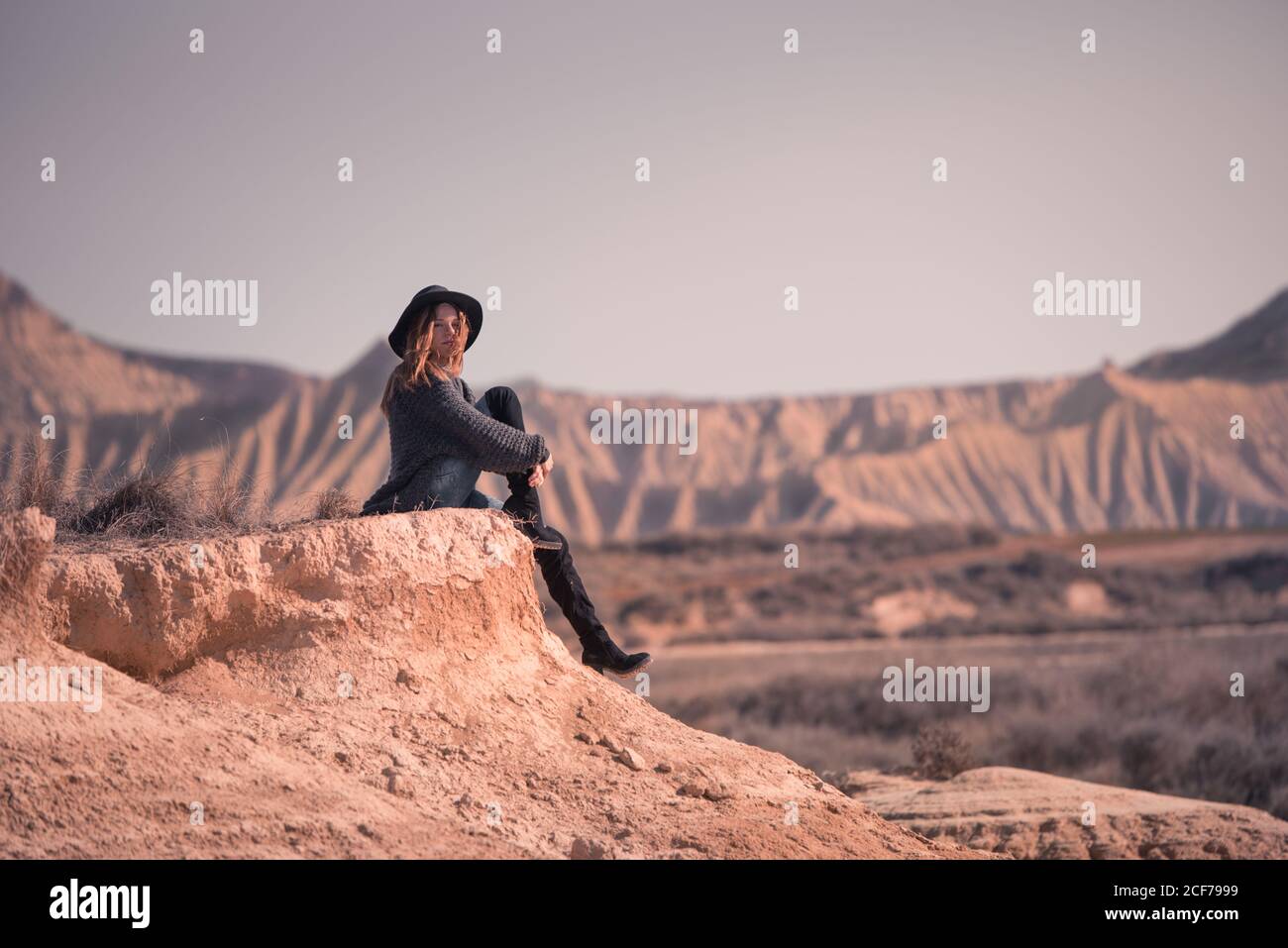 Donna elegante seduta sulla scogliera in badlands Foto Stock