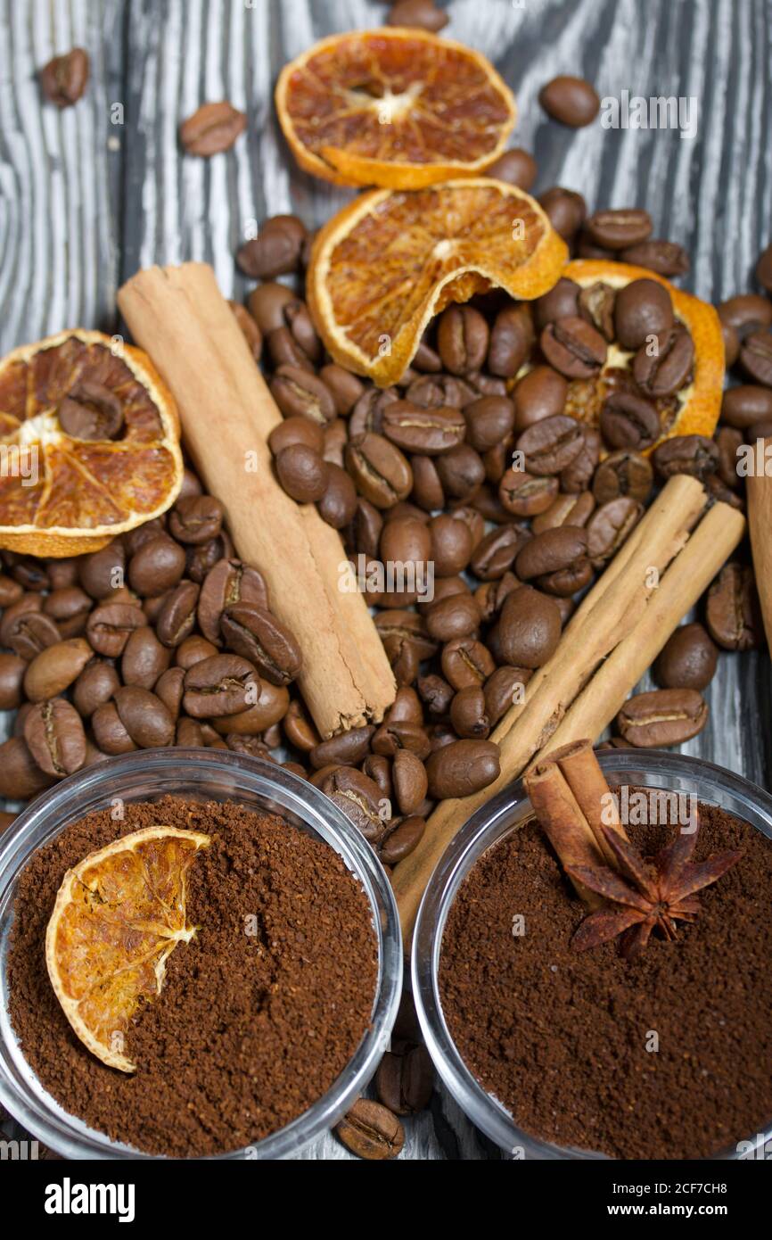 Chicchi di caffè. Caffè macinato in contenitori e spezie. Su una superficie di tavole di pino spazzolato dipinte in bianco e nero. Foto Stock