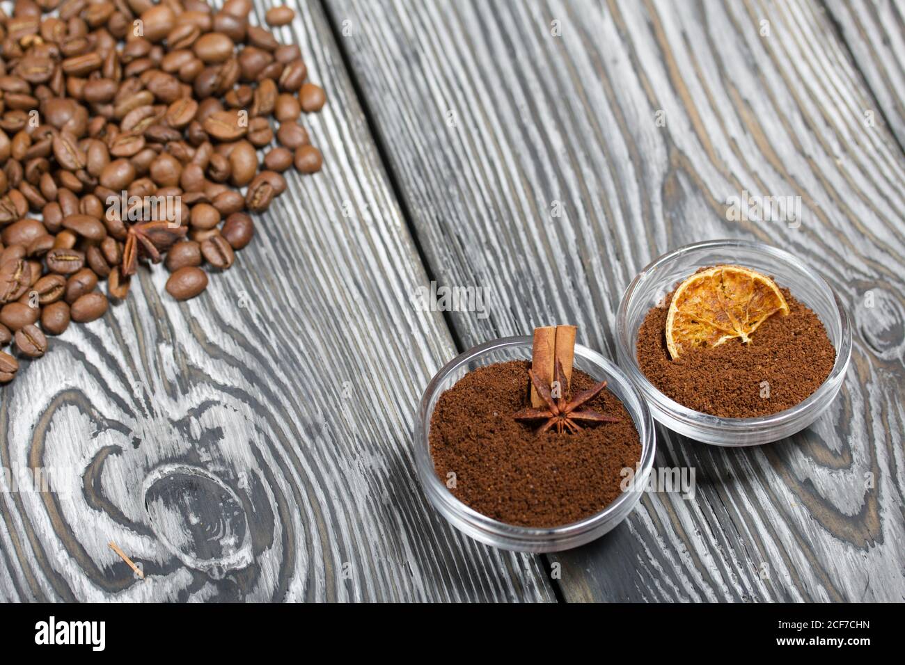 Chicchi di caffè. Caffè macinato in contenitori e spezie. Su una superficie di tavole di pino spazzolato dipinte in bianco e nero. Foto Stock