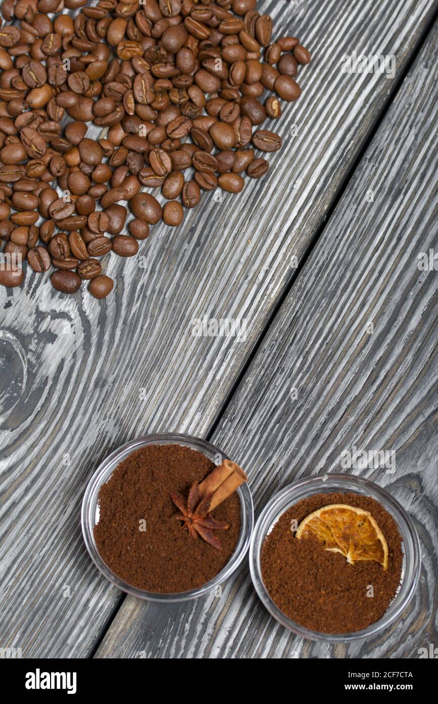 Chicchi di caffè. Caffè macinato in contenitori e spezie. Su una superficie di tavole di pino spazzolato dipinte in bianco e nero. Foto Stock