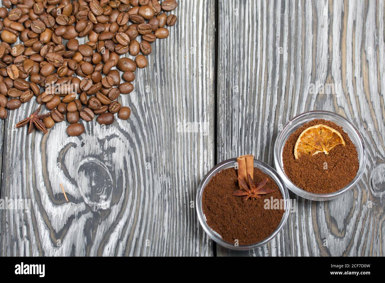 Chicchi di caffè. Caffè macinato in contenitori e spezie. Su una superficie di tavole di pino spazzolato dipinte in bianco e nero. Foto Stock